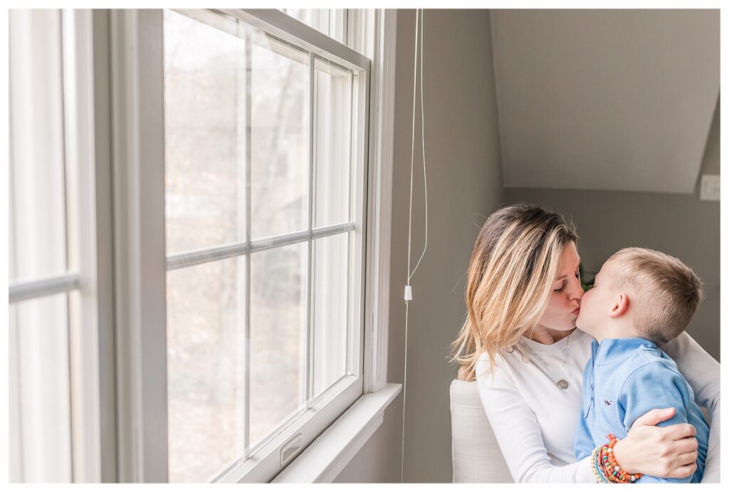 mom and son kiss by window