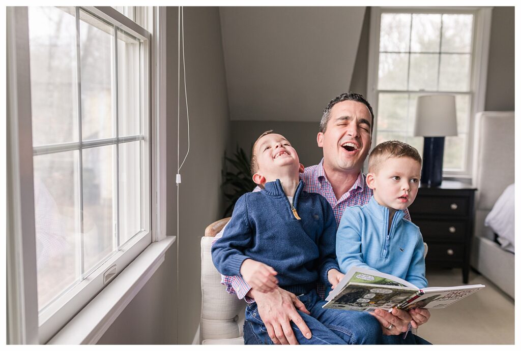 dad and sons laugh together reading a book