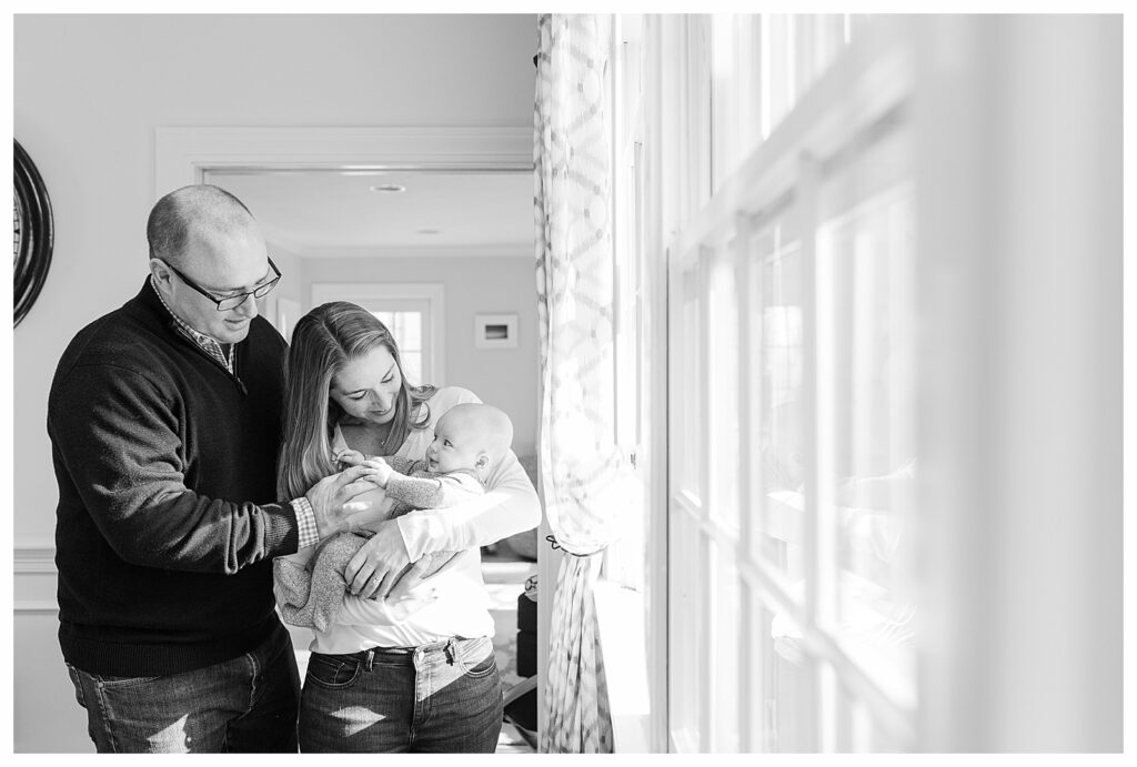 Needham MA family cuddles baby by window for photo 