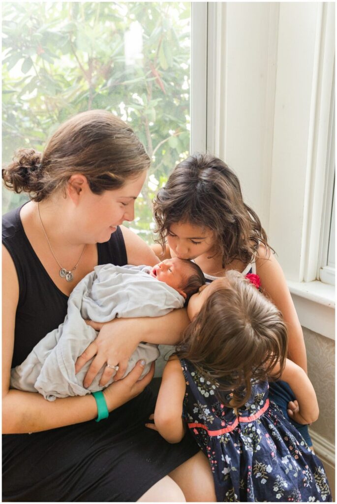 Natick Mom holds newborn, two big sisters kiss baby