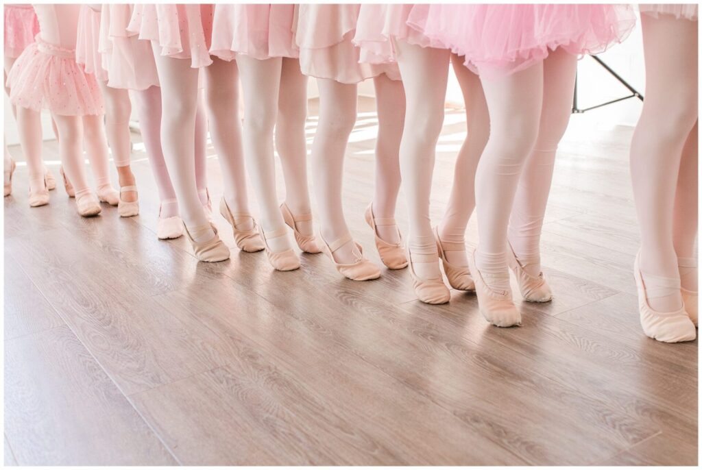 Ballerina's stand on toes in a line, just see tutus, legs and feet. DanceFIT Studio Natick MA