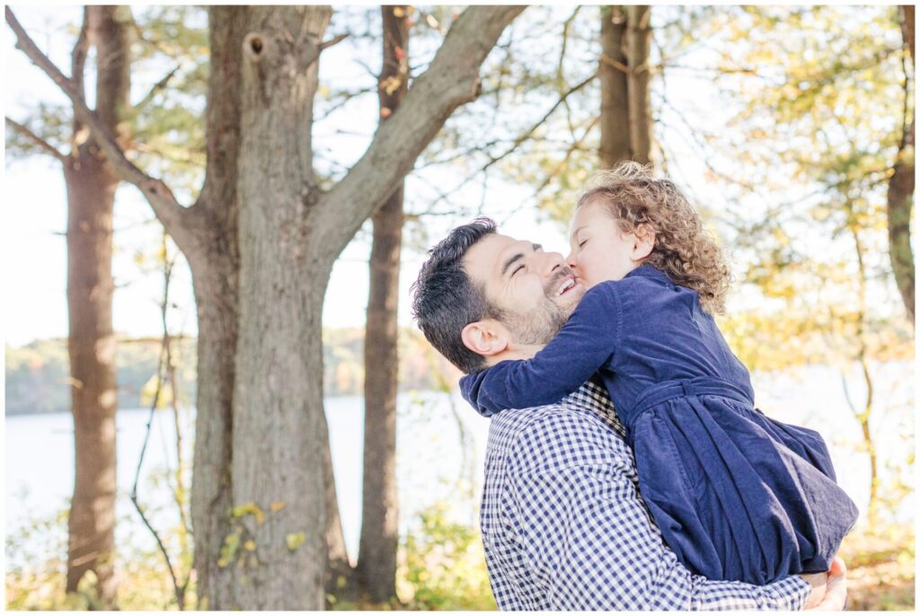 father holds daugher while she kisses him on the cheek. Morning light family photos Farm Pond Park Framingham MA