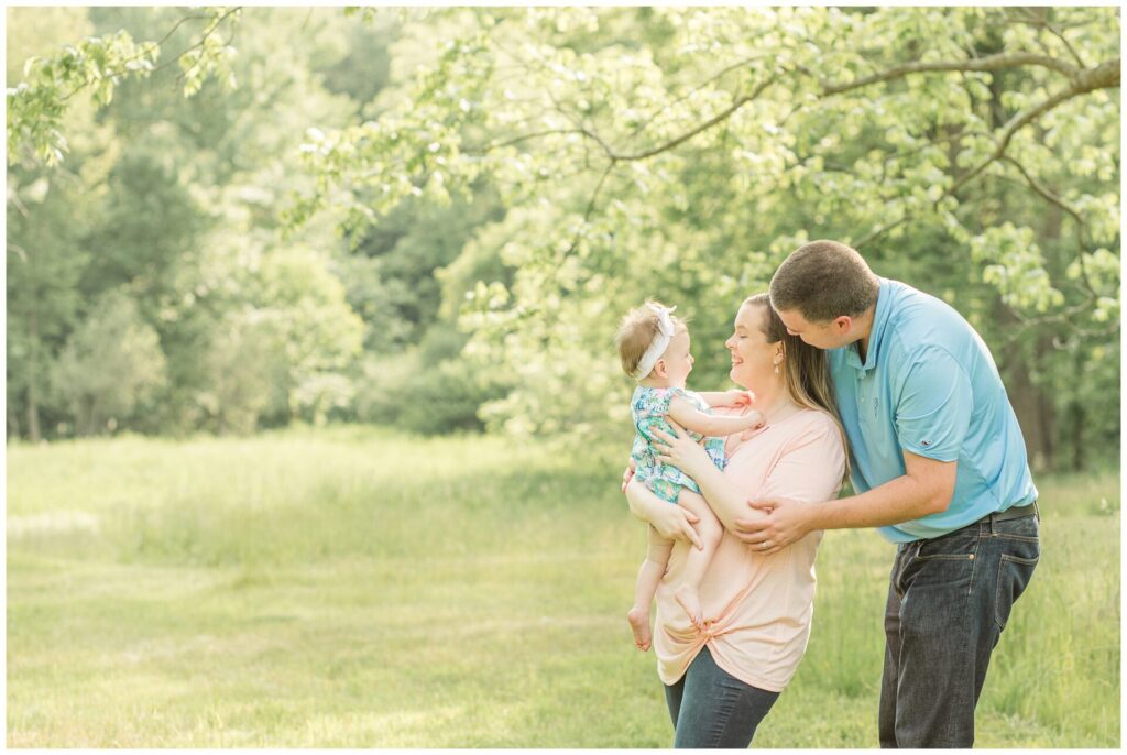 Parents smile at baby daughter for family photo at Barber Reservation Sherborn MA