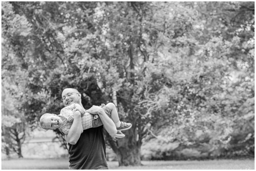 dad holds son upside down in black and while photo Massachusetts 