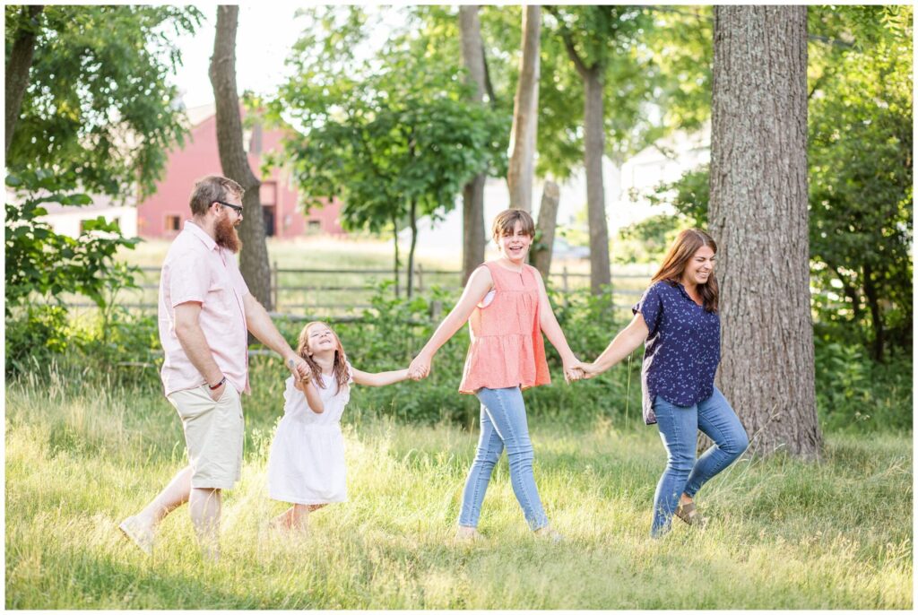 Natick MA family walks holding hands and laughing in picture 
