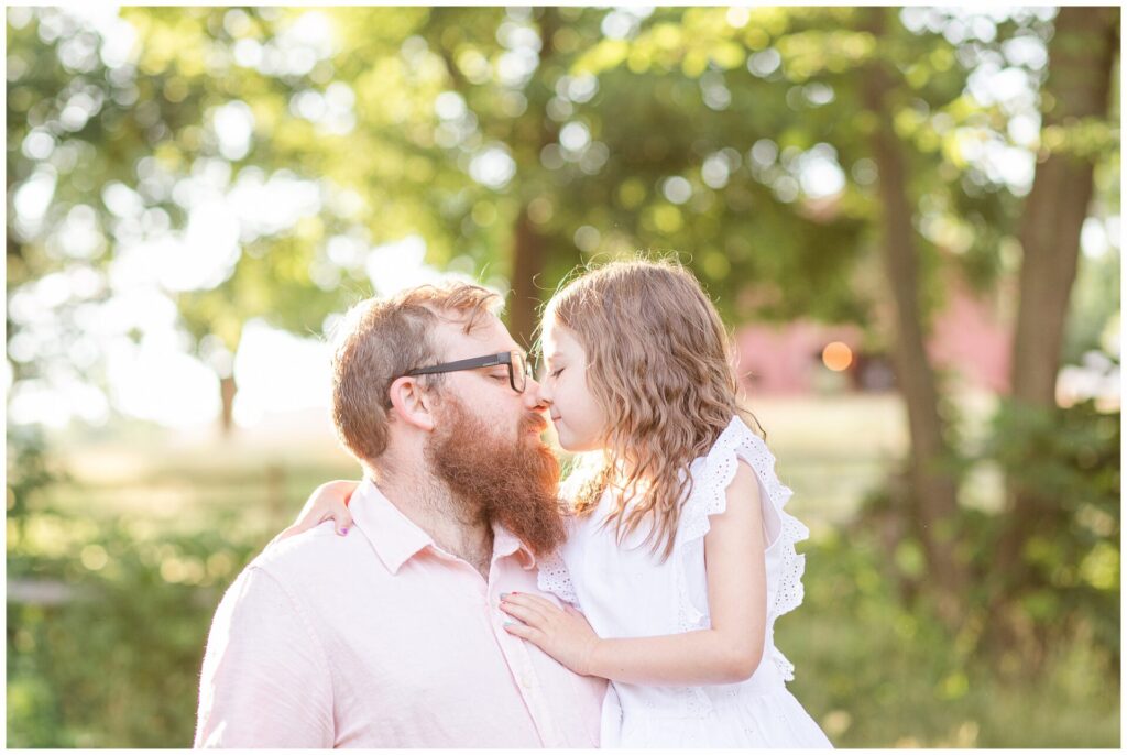 Father and daughter rub noses for family photo with morning light in Sherborn MA