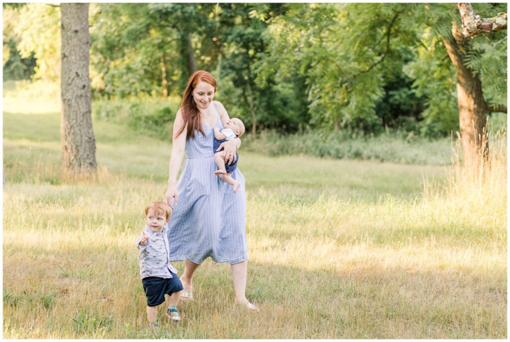 Mom holds baby and walks holding toddlers hand in Massachusetts during Family Photo session
