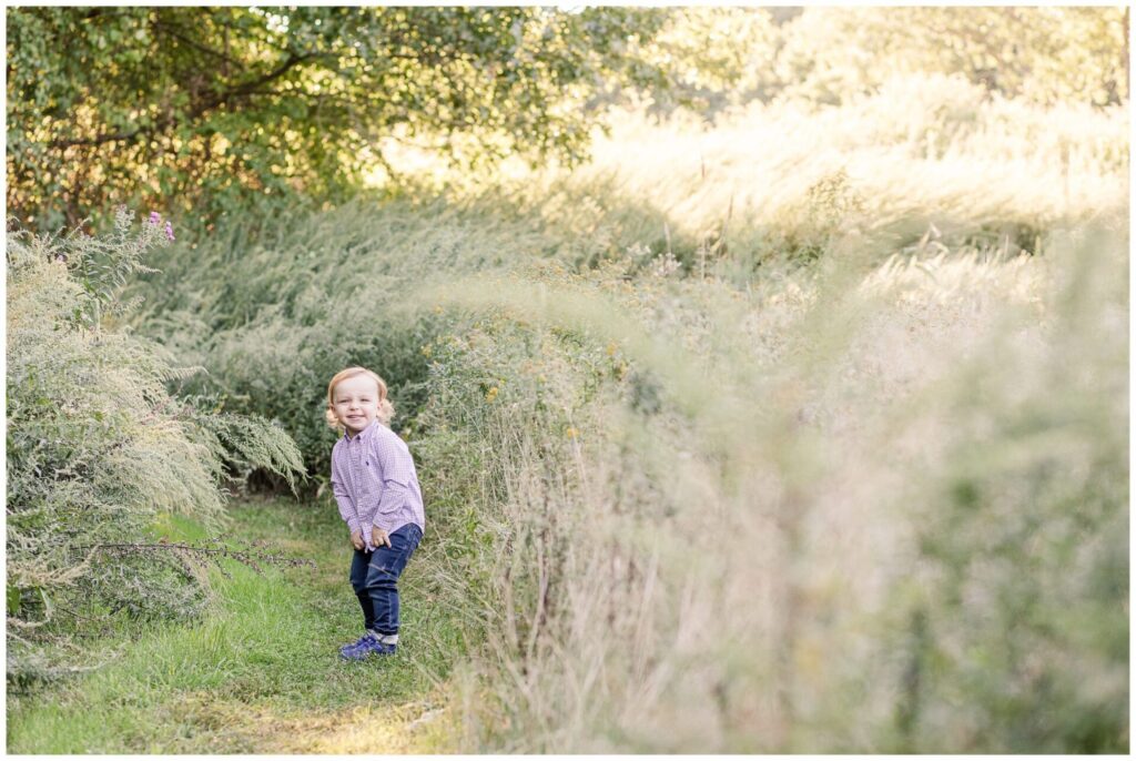 two year old in field in Newton Massachusetts smiling for photo