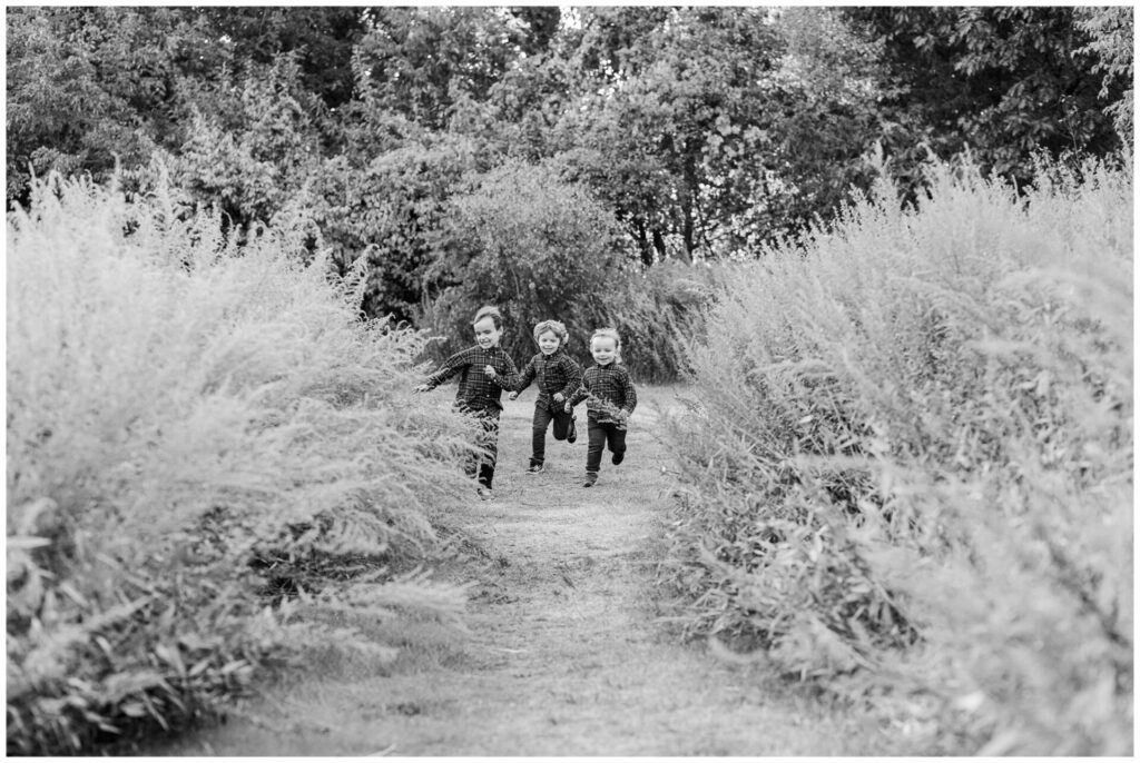 black and white photograph of three brothers running towards photographer