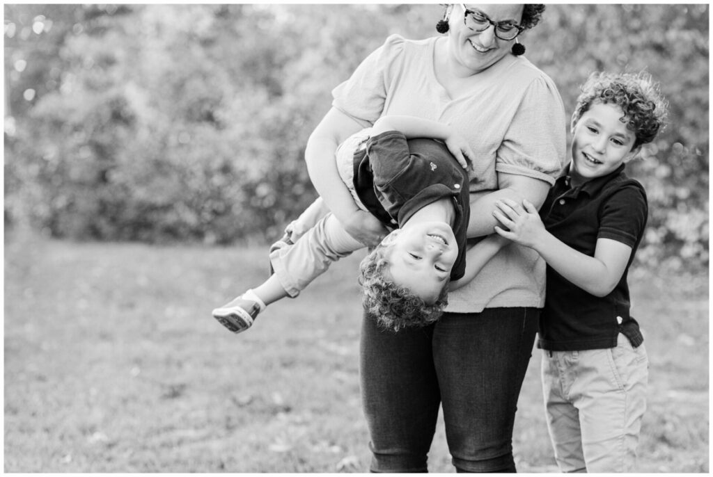 Black and white photo of mom playing with two sons for metro west Boston family photo session. 
