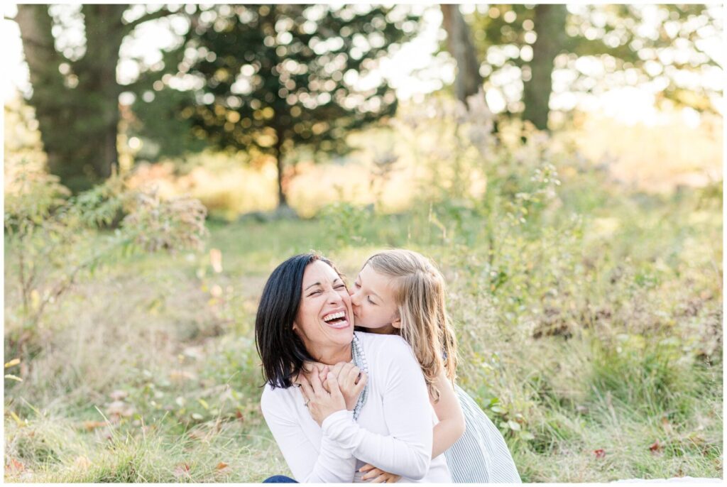 Mom laughing while daughter kisses her cheek photo, Wayland Massachusetts. 