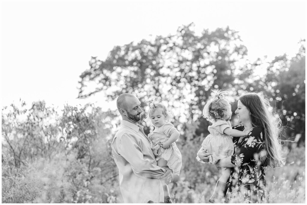 black and white photo of parents holding twin daughters for family photo in Wayland Massachusetts