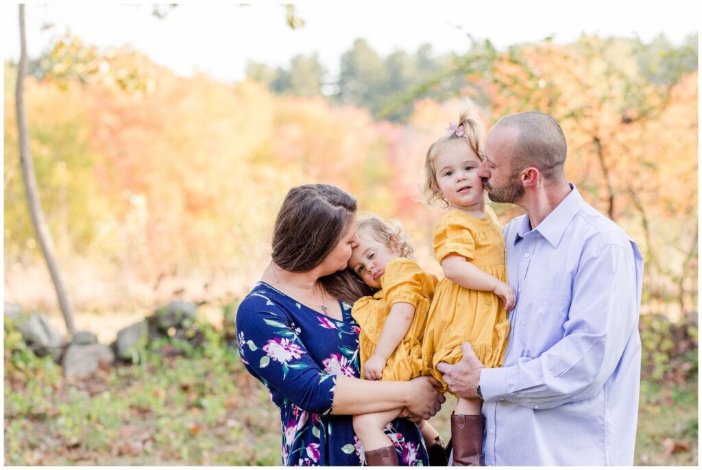 parents kiss twin daughters for family photo in Wayland Massachusetts
