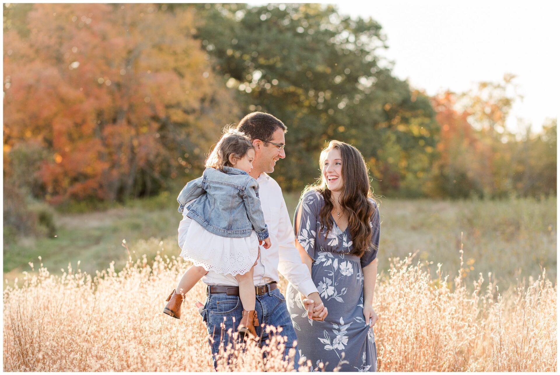 Family walks through field laughing together maternity family photo Wayland Massachusetts
