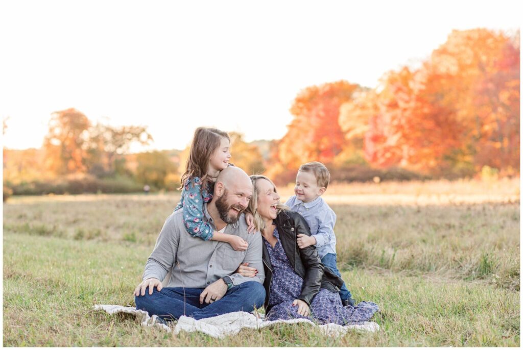 Natick Massachusetts family laughs together on a blanket in field for Maternity family photo session