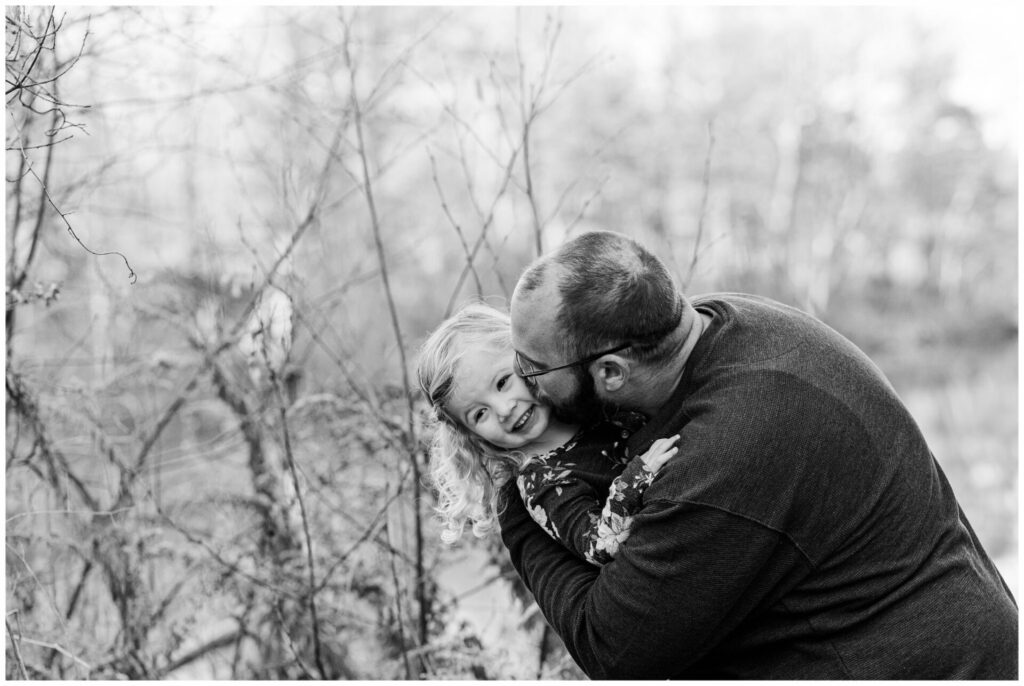black and white photo of dad kissing daughter during cold weather family photo session
