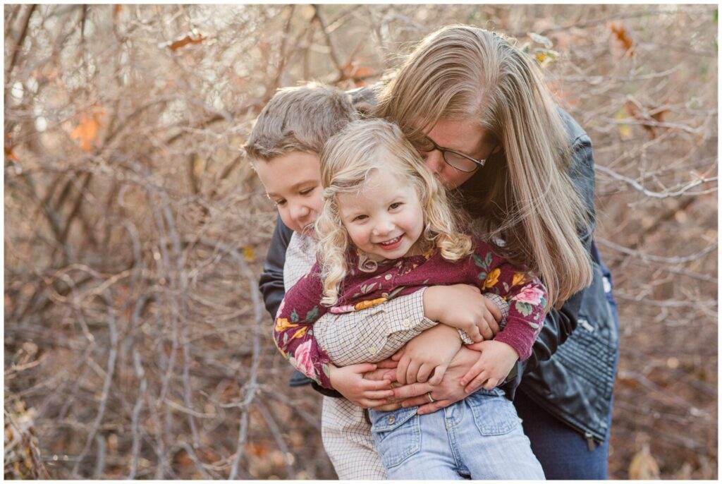 photo of mom hugging and kissing her kids during cold weather family photo session in Natick MA