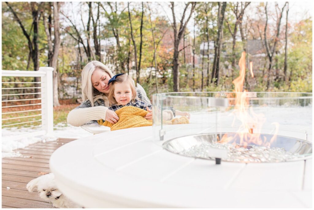 Mom and daughter sit by fire during snowy Natick Massachusetts family photo session
