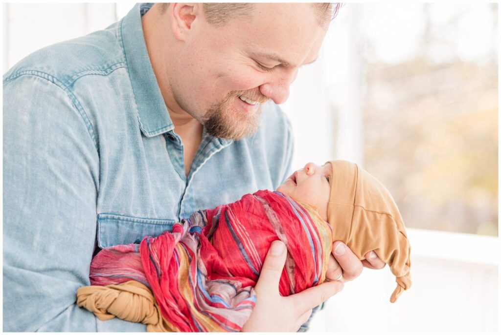 Dad smiling at newborn baby for photo session 