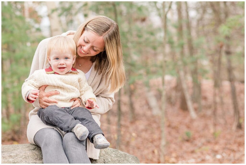 one year old sits on mom lap for MetroWest Boston bump to one year photo session
