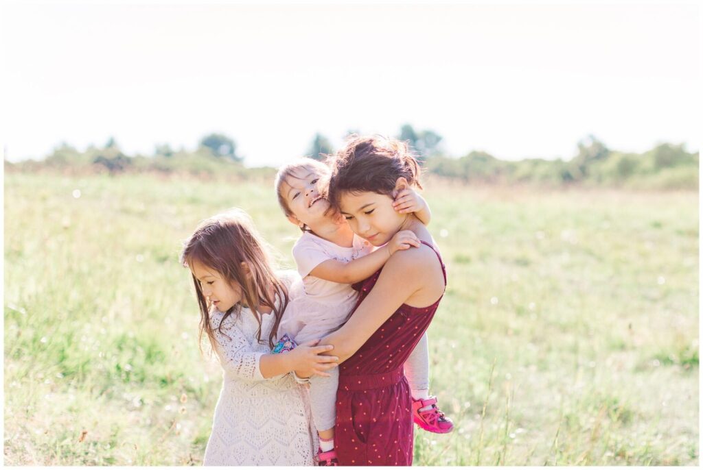 three sisters hugging in field in Dover Massachusetts