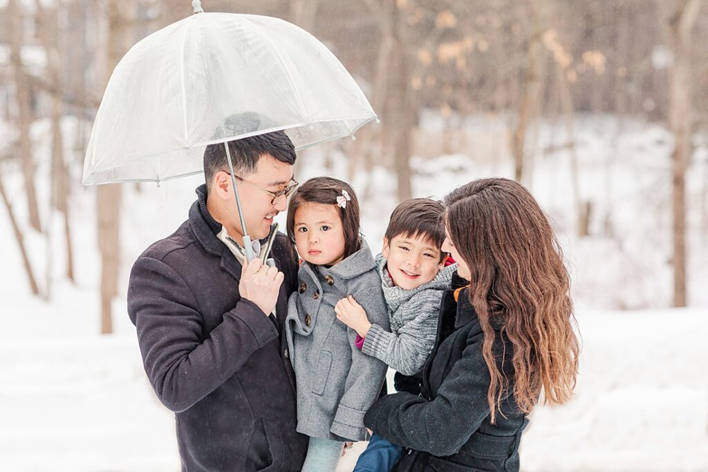Family smiles at each other for photographer during family photos in the snow in Natick Massachusetts