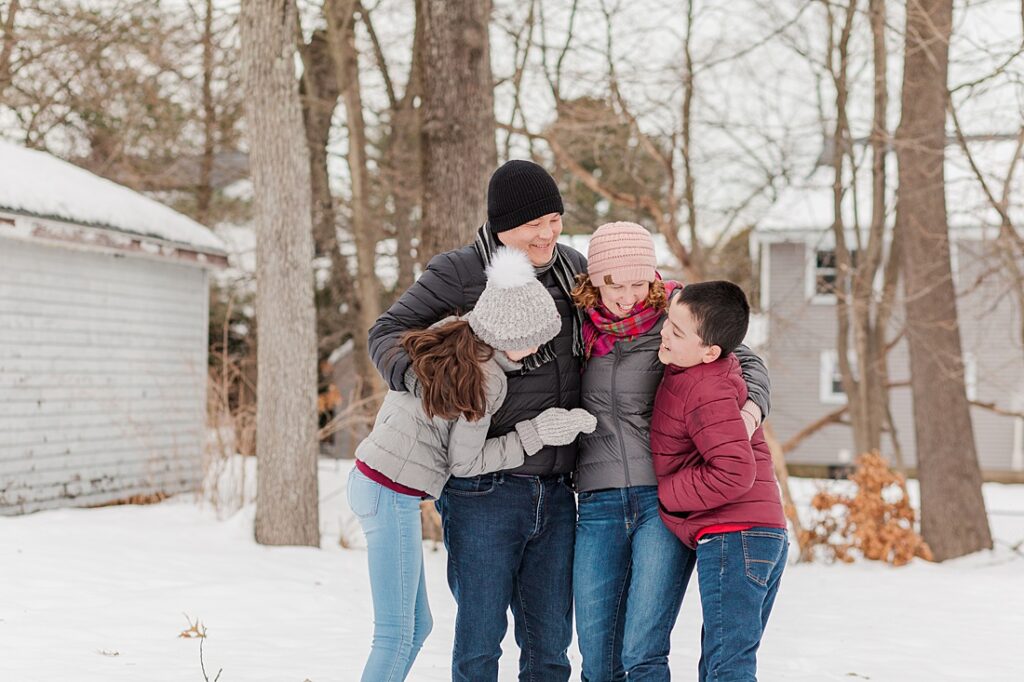 family smiles together in the snow during family photo session in Natick Massachusetts