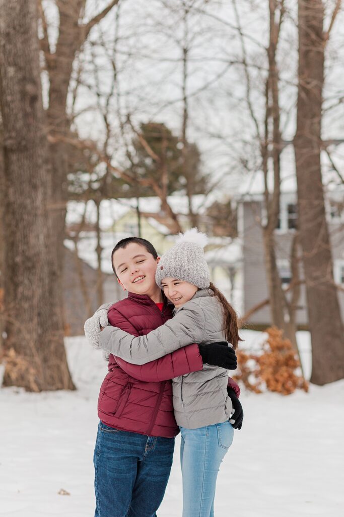 Siblings hug in the snow for Natick MA family photographer for photos for NICU blog