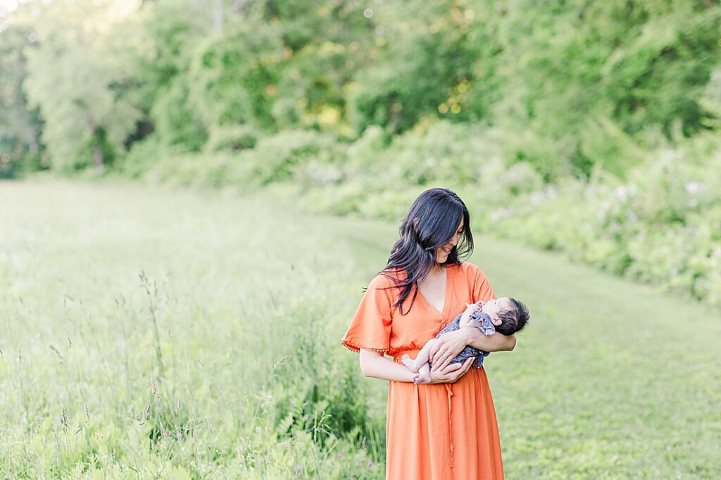 Mom smiles at baby in field of tall grass at Heard Farm, Wayland Massachusetts