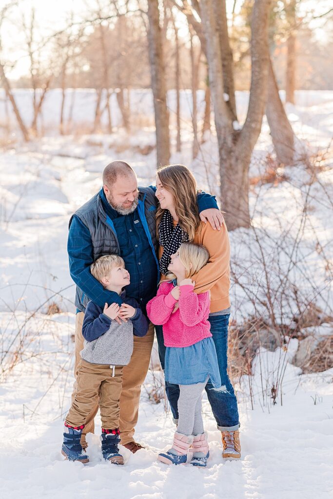 Family smiles together during winter photo session at Wayside Inn Grist Mill, Sudbury MA