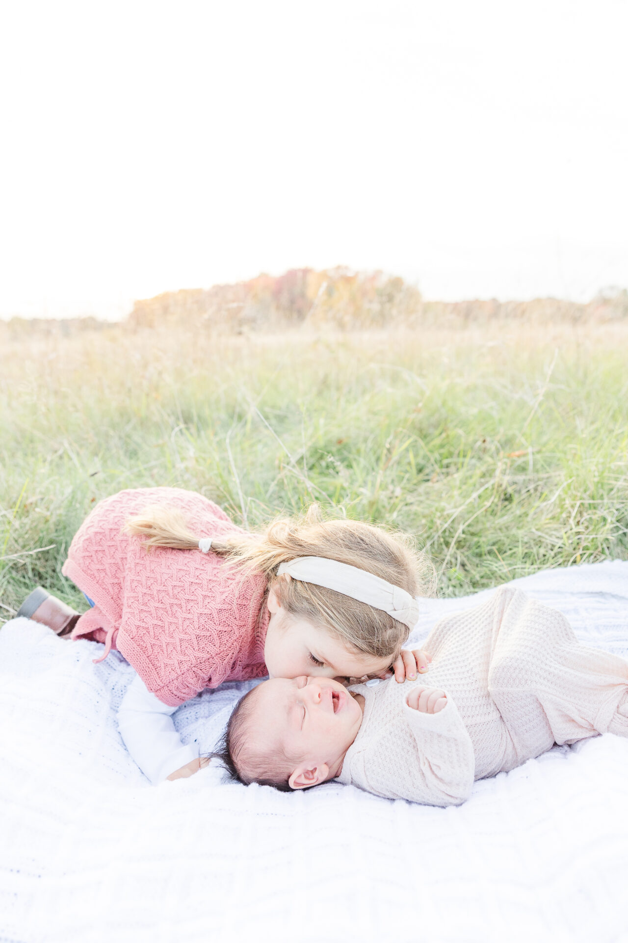 girl kisses baby during outdoor newborn photo session in Wayland MA with Sara Sniderman Photography