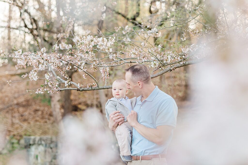 Father holding son by flowering tree during family photo session with Sara Sniderman Photography at South Natick Falls, Natick Massachusetts