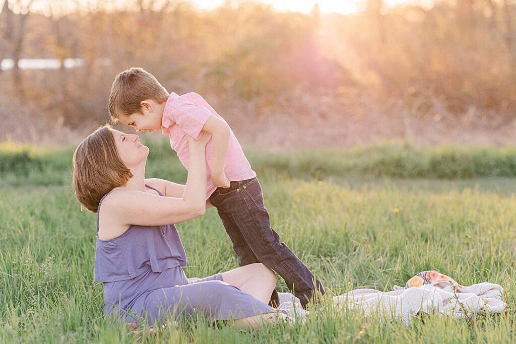 Mom and son touch noses on a blanket in a field during family photo session with Sara Sniderman Photography at Heard Farm, Wayland Massachusetts