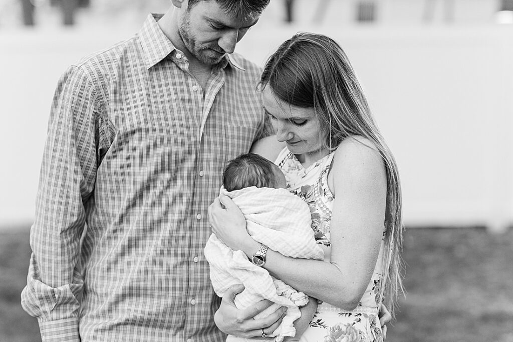 black and white of parents holding newborn during outdoor newborn photo session in Natick Massachusetts with Sara Sniderman Photography. 