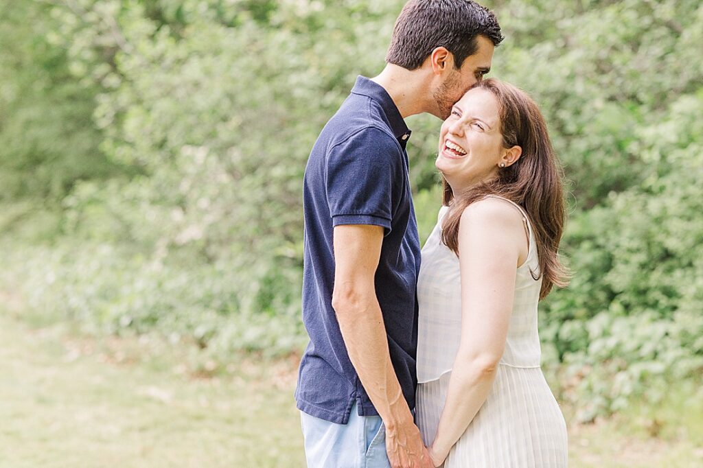 Woman laughs while husband whispers in her ear during family photo session at Elm Bank, Wellesley Massachusetts with Sara Sniderman Photography