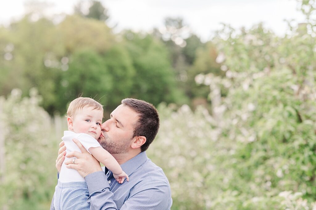 Father kisses son during family photo session with Sara Sniderman Photography at Dowse Orchard, Sherborn Massachusetts