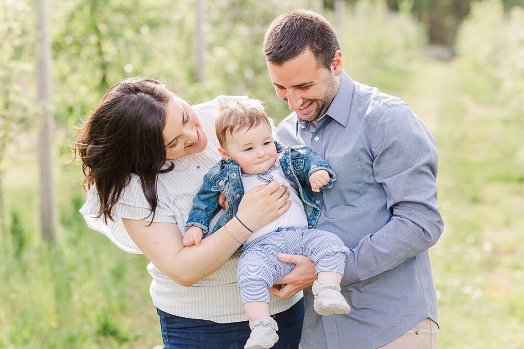 Parents smile at baby son during family photo session with Sara Sniderman Photography at Dowse Orchard, Sherborn Massachusetts