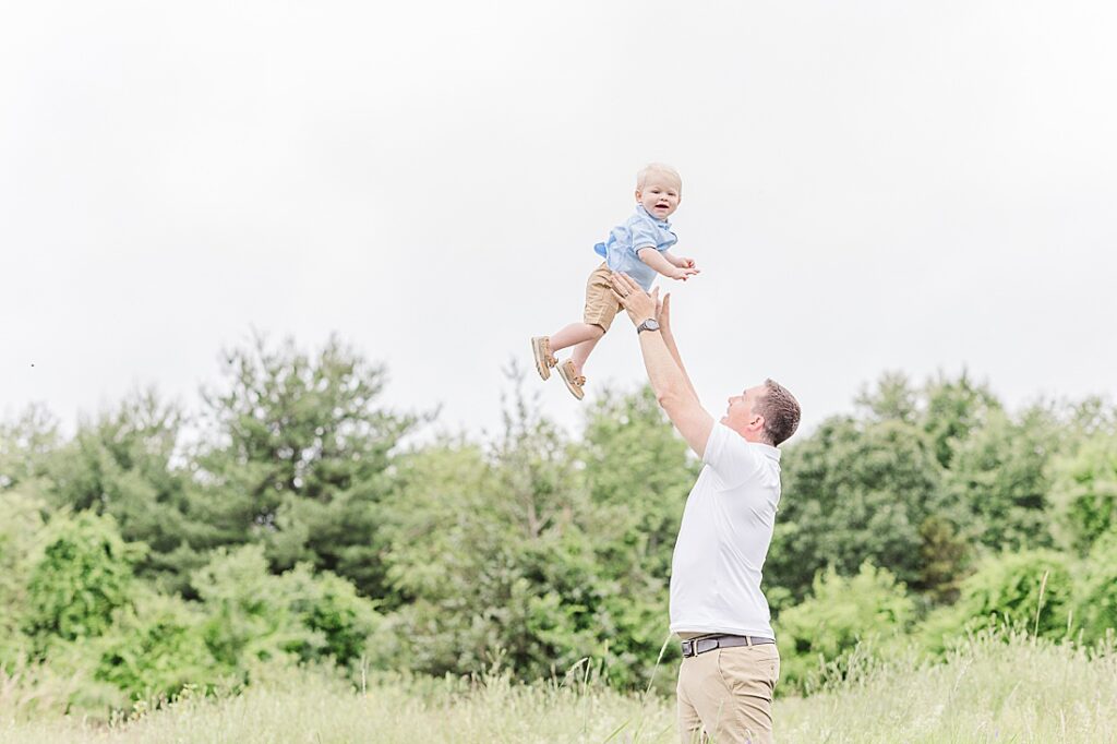 Dad throws son into the air during full family photo session with Sara Sniderman Photography at Oak Grove Park, Millis Massachusetts