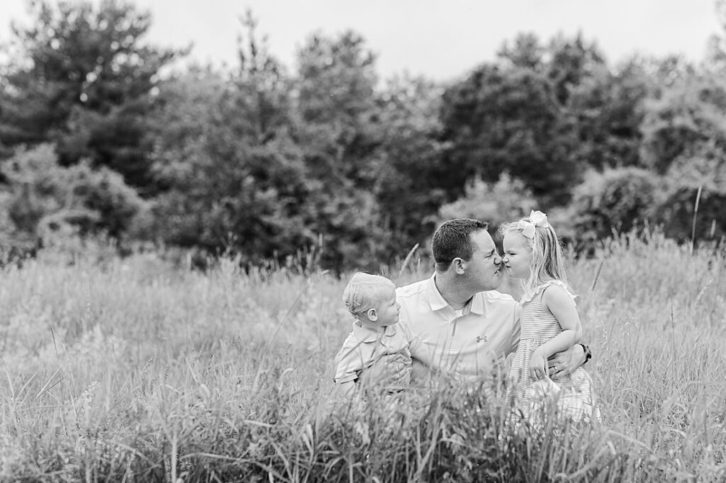 black and white of dad rubbing noses with daughter in field during full family photo session with Sara Sniderman Photography at Oak Grove Park, Millis Massachusetts