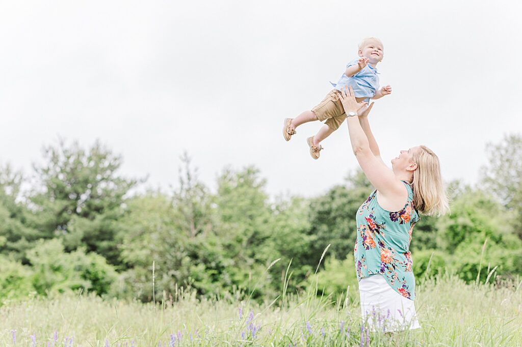 mom throws son into the air during full family photo session with Sara Sniderman Photography at Oak Grove Park, Millis Massachusetts