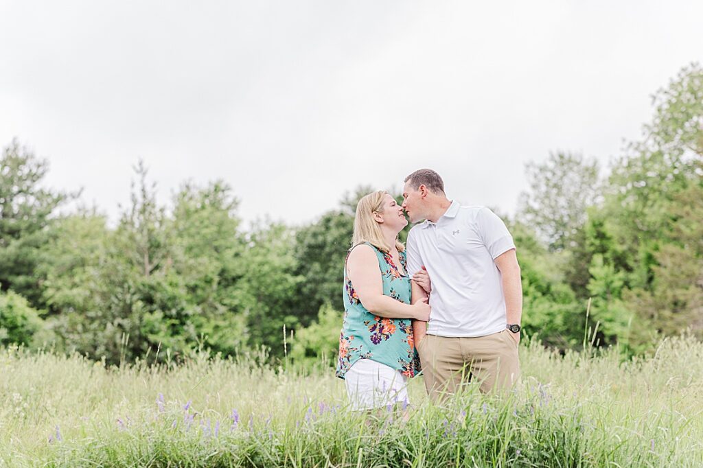 parents kiss in field during full family photo session with Sara Sniderman Photography at Oak Grove Park, Millis Massachusetts