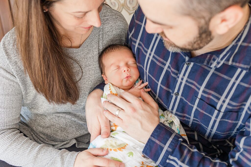 Parents hold baby during in home newborn photo session with Sara Sniderman Photography in Framingham Massachusetts