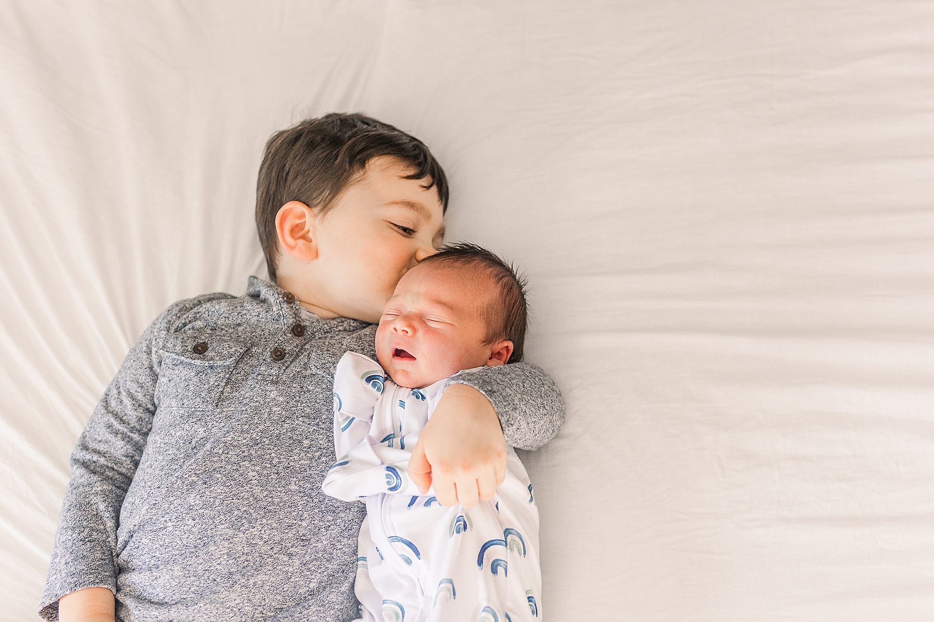 big brother kisses baby during in home newborn photo session with Sara Sniderman Photography in Framingham Massachusetts