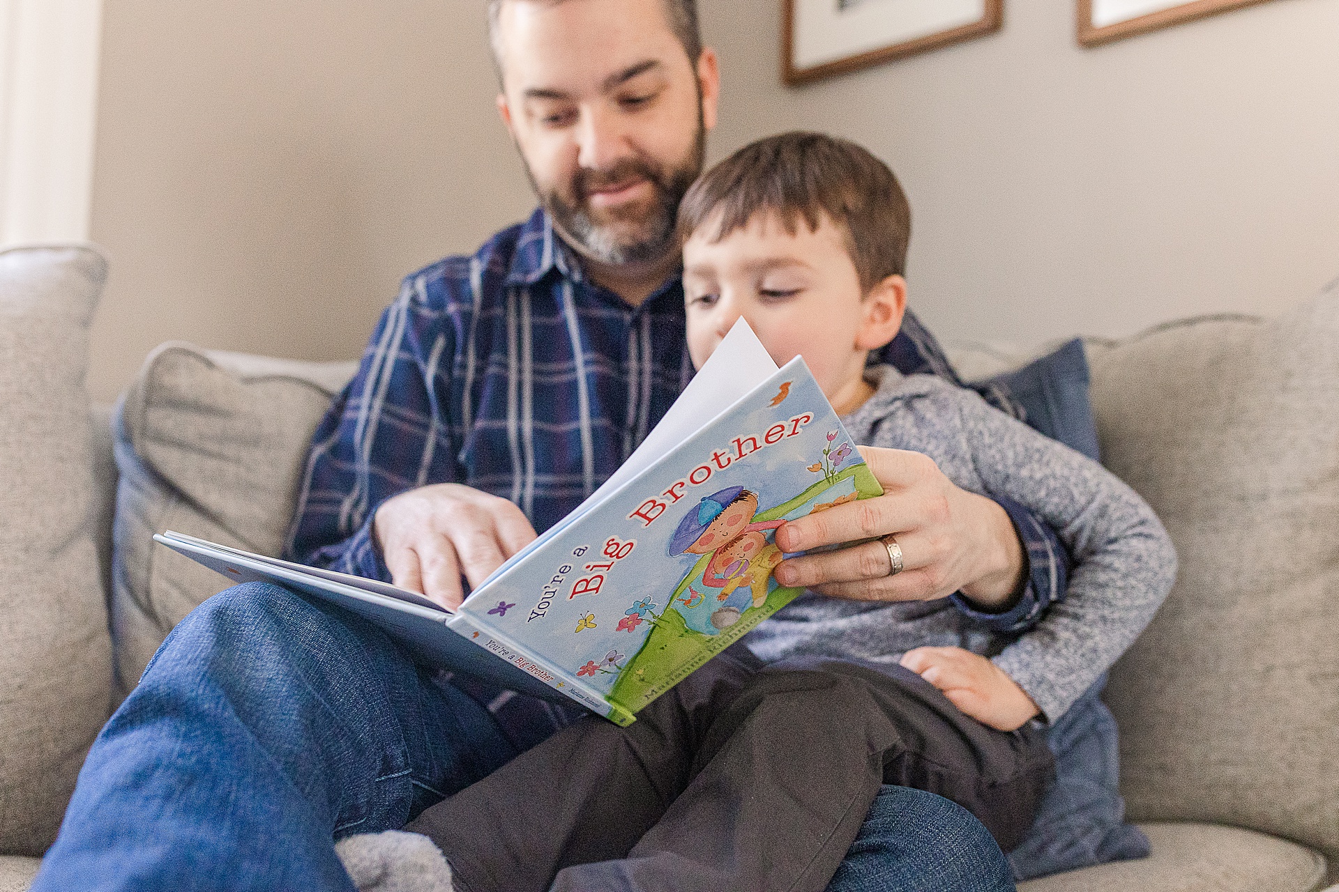 Dad reads big brother book with son during in home newborn photo session with Sara Sniderman Photography in Framingham Massachusetts