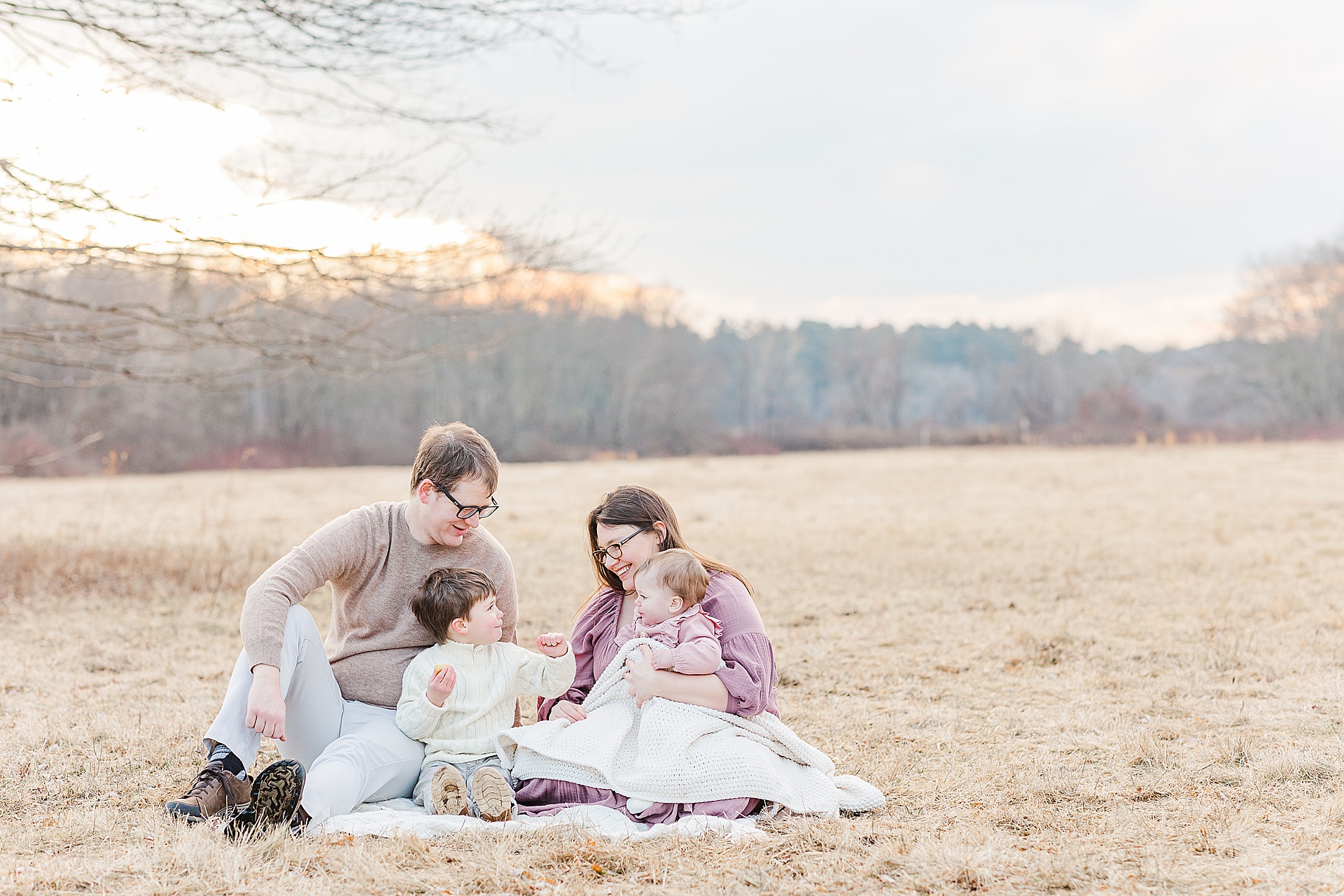 family snuggles on a blanket during first birthday cake smash photo session with Sara Sniderman Photography at Cow Common, Wayland Massachusetts