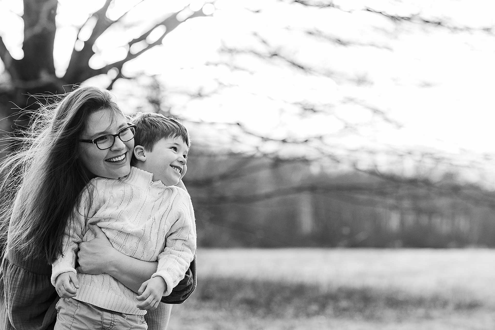 black and white photo of mom hugging son during first birthday cake smash photo session with Sara Sniderman Photography at Cow Common, Wayland Massachusetts
