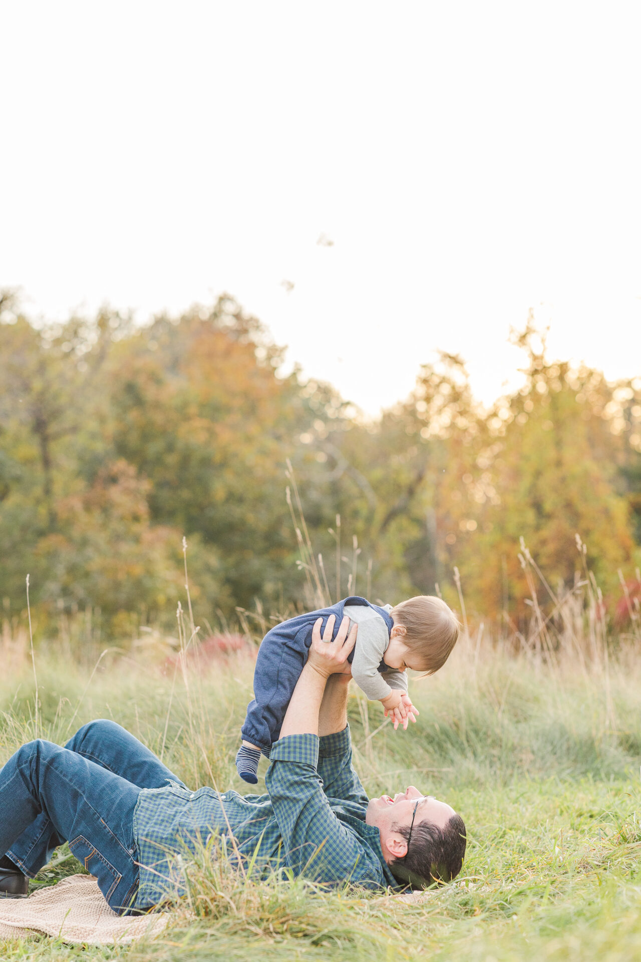 dad holds son above his head during family photo session with Sara Sniderman Photography in Natick Massachusetts