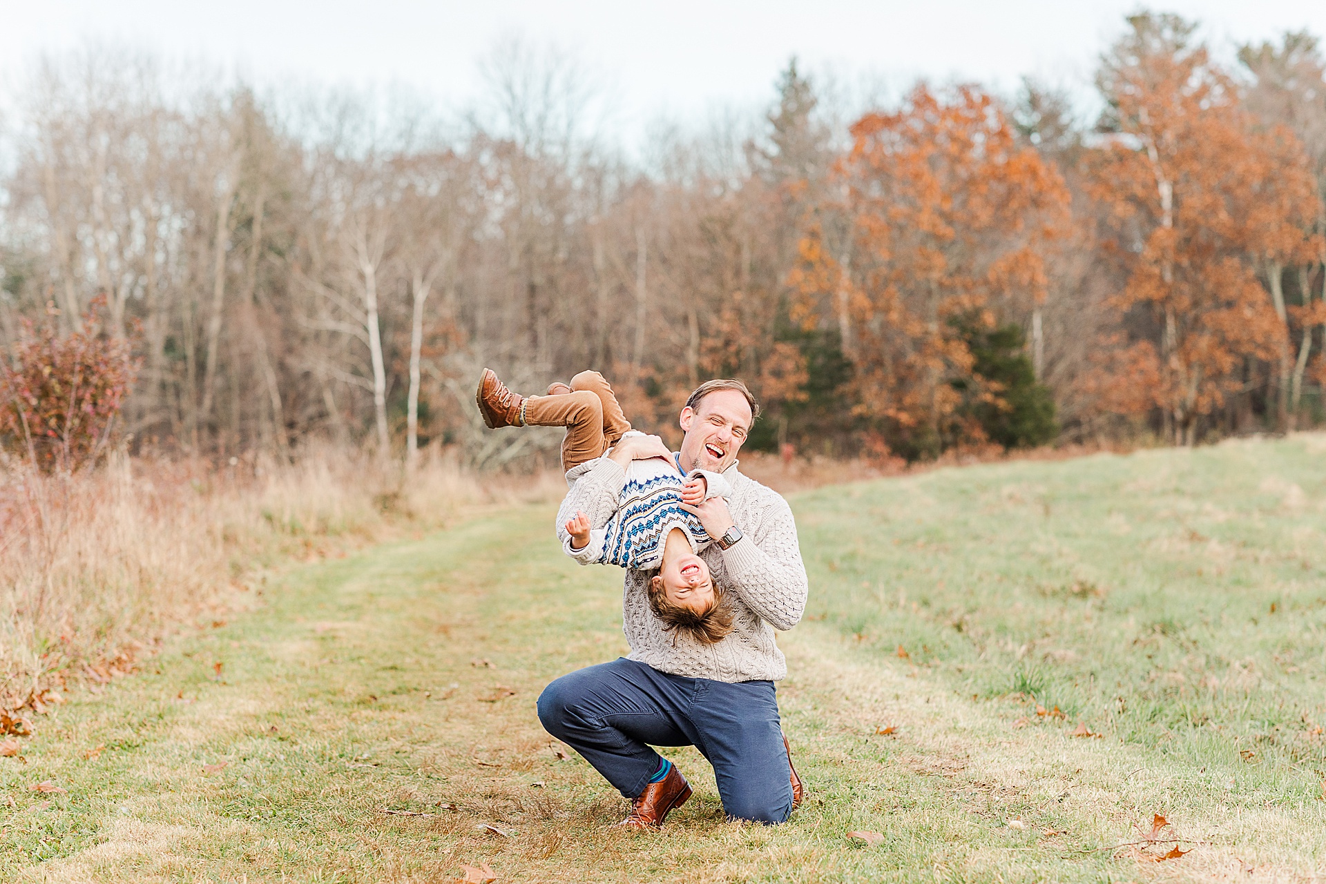 dad holds son upside down during family photo session with Sara Sniderman Photography at Breakneck HIll Reservation, Southboro Massachusetts