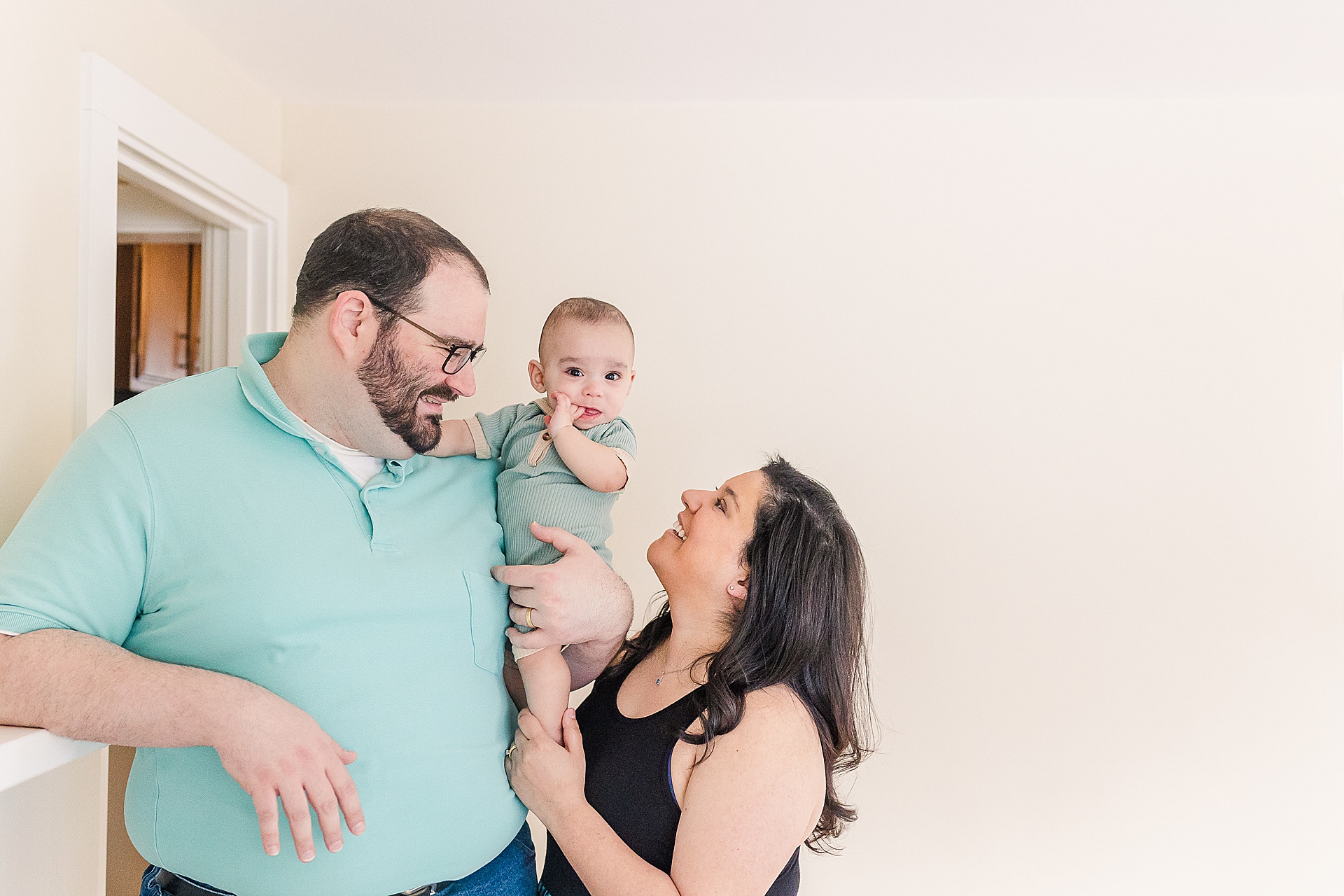 Parents smile at baby during in home photo session with Sara Sniderman Photography in Natick Massachusetts