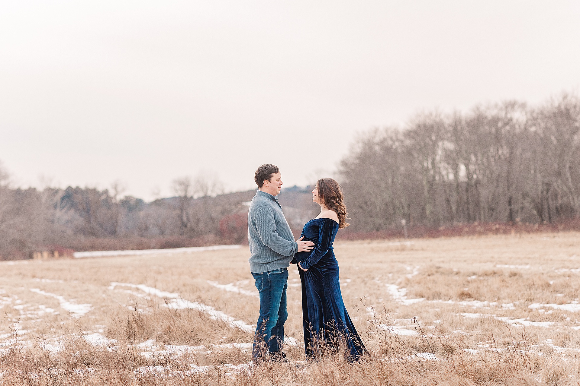 pregnant woman and husband stand if field during photo session with Sara Sniderman Photography at Cow Common, Wayland Massachusetts